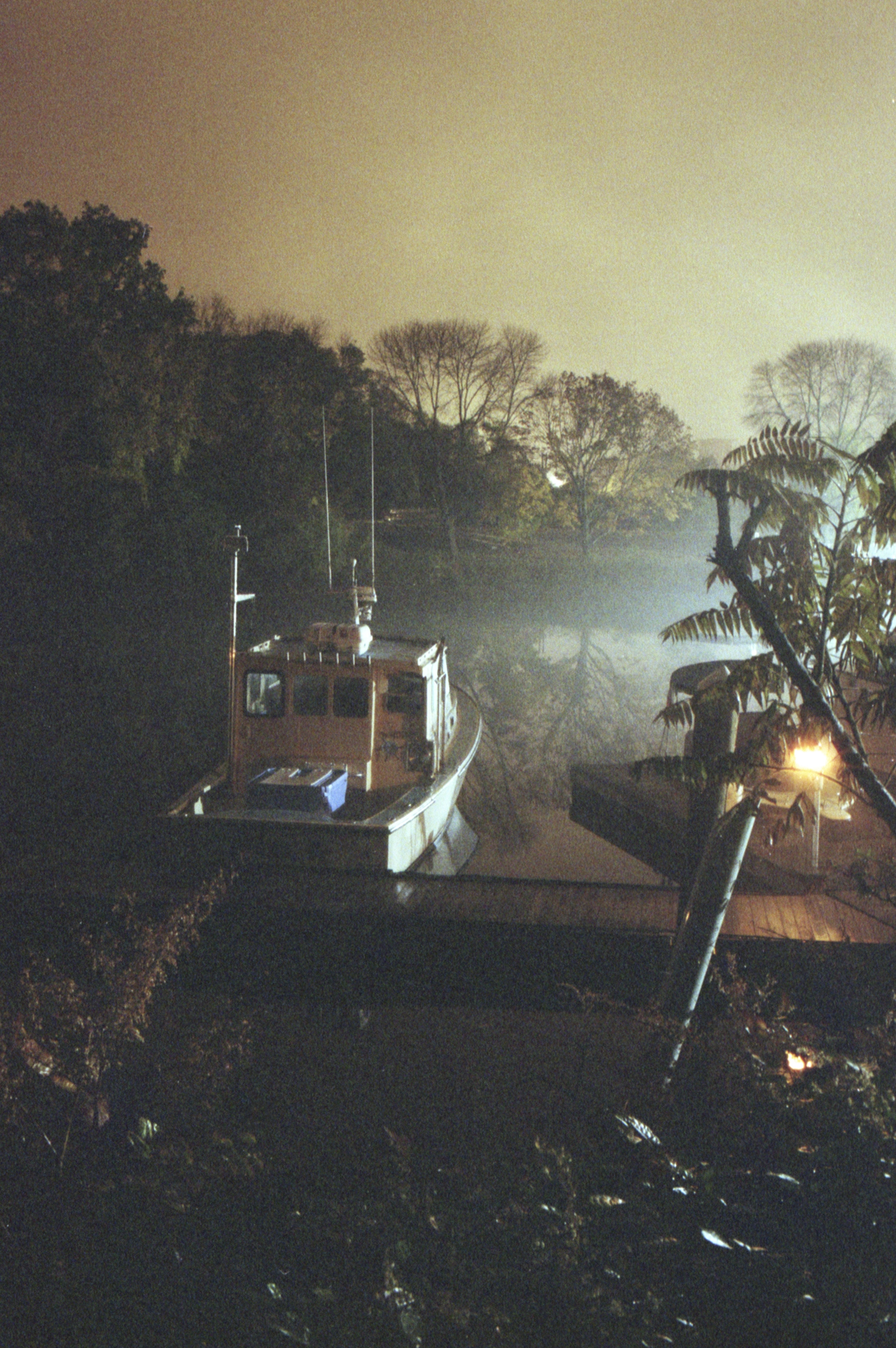 photograph of a fishing boat at at river dock at night