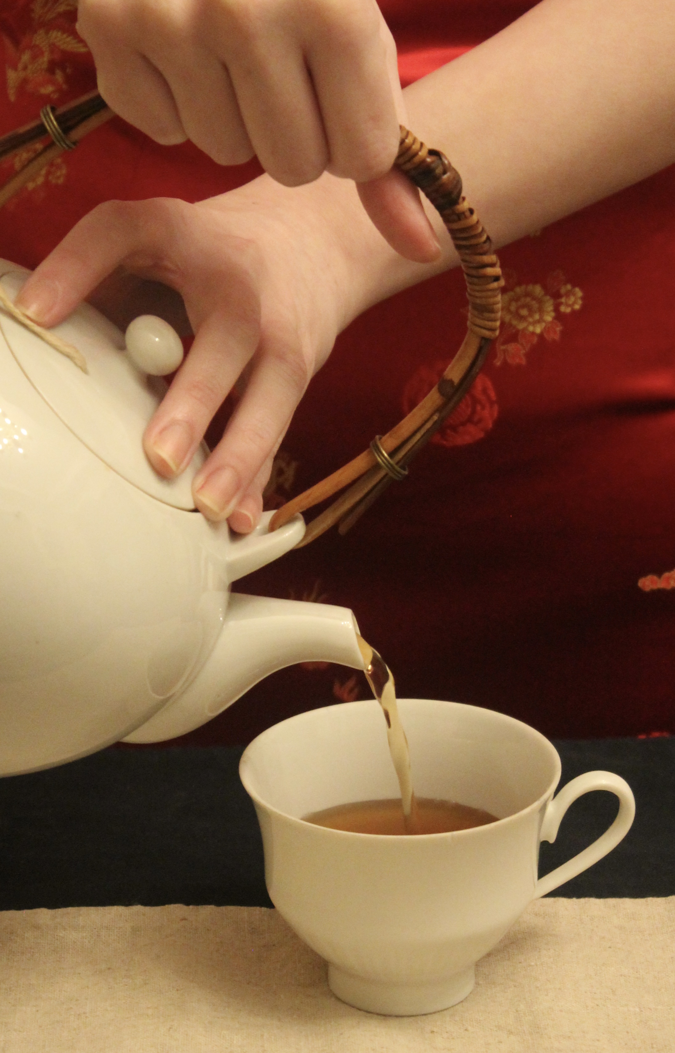 photograph of a person pouring tea into a teacup